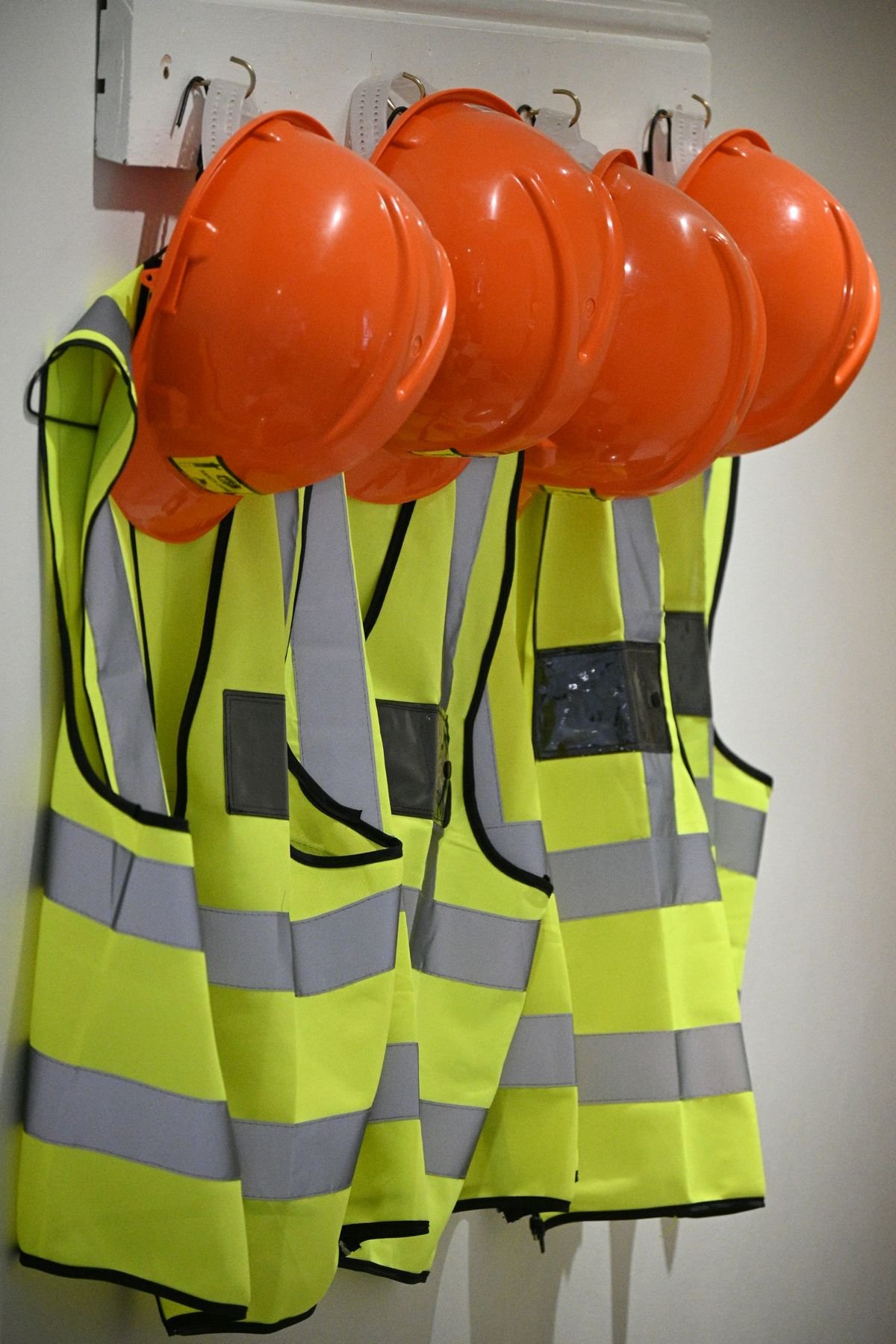 Cascos y chalecos de seguridad colgados en una pared